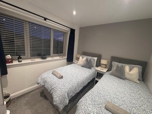 a bedroom with two beds and a window at Abbey’s Inn in Cheadle