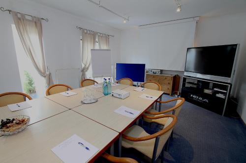 a conference room with a table with chairs and a television at Hotel Lindemann in Bad Nauheim