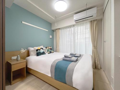 a bedroom with a bed with blue walls and a window at nestay inn tokyo ueno in Tokyo