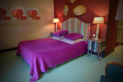a bedroom with a purple bed with two purple pillows at Petit Garros in Fronsac