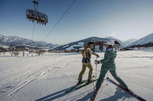 two people on skis in the snow with a ski lift at Hotel Waldfrieden in Schladming