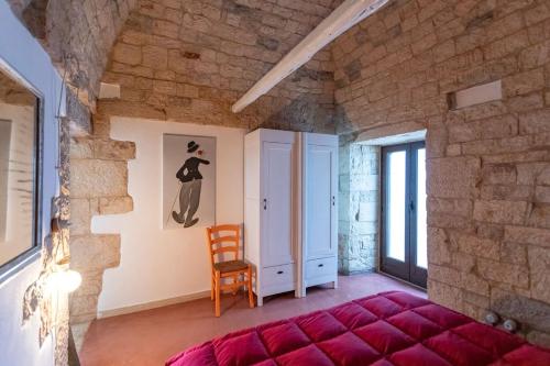 a room with a red bed and a chair at Trullo Franza - Salento Reservation in Torre Suda