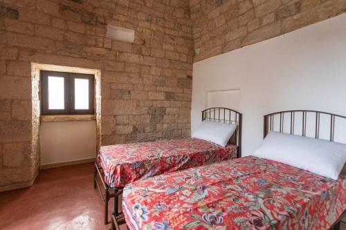 two beds in a room with a brick wall at Trullo Franza - Salento Reservation in Torre Suda