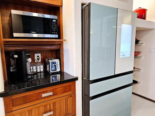 a kitchen with a refrigerator and a microwave at Breathtaking Oceanfront Home on Lava Rock Beach in Pahoa