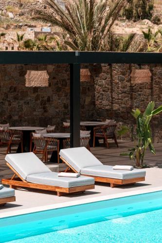 a group of lounge chairs next to a swimming pool at Muse οf Mykonos Luxury Suites in Mýkonos City