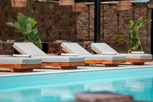 a row of chaise lounge chairs next to a swimming pool at Muse οf Mykonos Luxury Suites in Mýkonos City