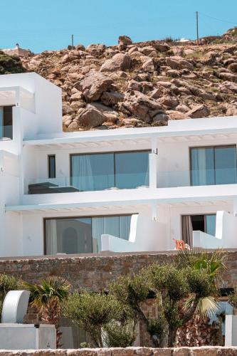 a white house with a hill in the background at Muse οf Mykonos Luxury Suites in Mýkonos City