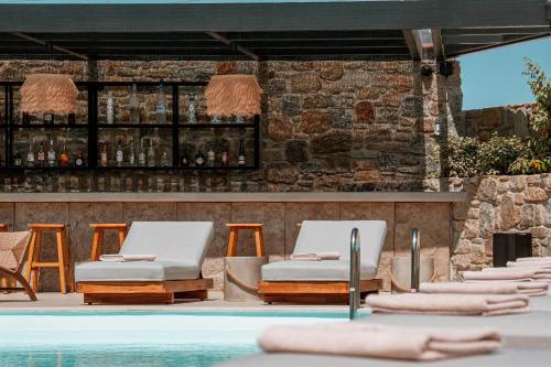 a pool with lounge chairs and a bar at Muse οf Mykonos Luxury Suites in Mýkonos City
