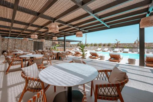 a patio with tables and chairs and a pool at Muse οf Mykonos Luxury Suites in Mýkonos City