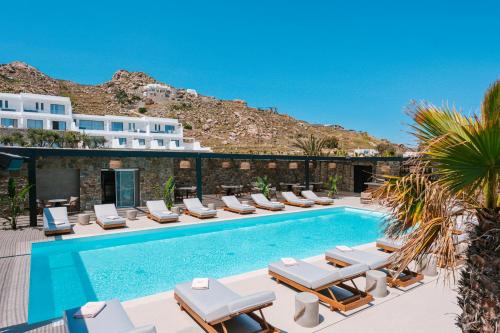 a pool with lounge chairs and a resort at Muse οf Mykonos Luxury Suites in Mýkonos City