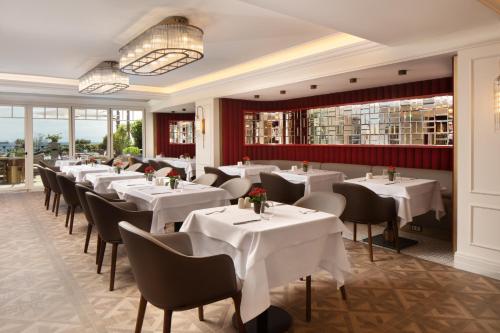 a restaurant with white tables and chairs and windows at Mula Hotel in Istanbul