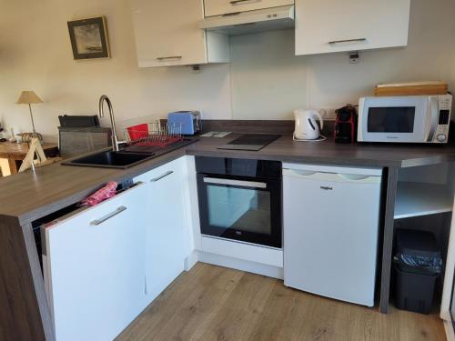 - une cuisine avec un comptoir, un four micro-ondes et un évier dans l'établissement Tipoz'Immo-Le Cocon direct access beach-spot surf, à Pouldreuzic