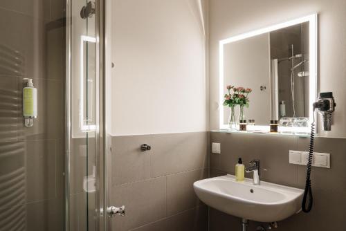 a bathroom with a sink and a shower with a mirror at Hotel Meersinn - Binz in Binz