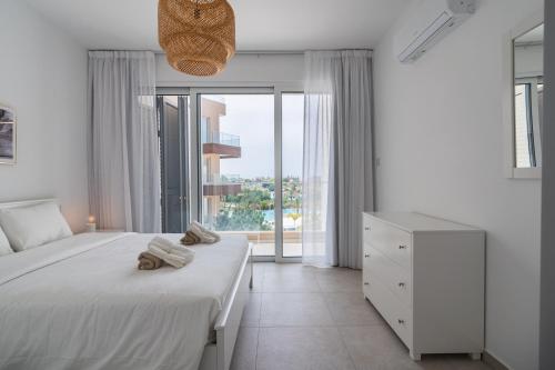 Un dormitorio blanco con una cama y una ventana. en Elegant villa with pool view, en Klorakas