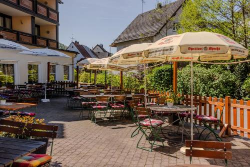 an outdoor patio with tables and chairs and umbrellas at Landgasthof zur Linde in Heimbuchenthal