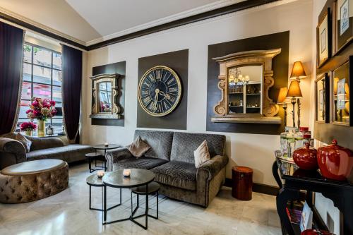 a living room with a couch and a clock on the wall at Le Cavendish in Cannes