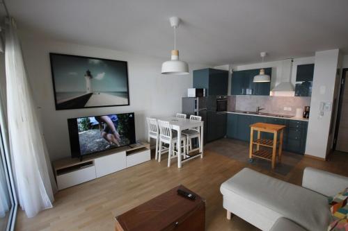 un salon avec un canapé et une télévision et une cuisine dans l'établissement Appartement T3 66 m2 residence L'univers centre-ville 2 chambres garage et terrasse, à Aix-les-Bains
