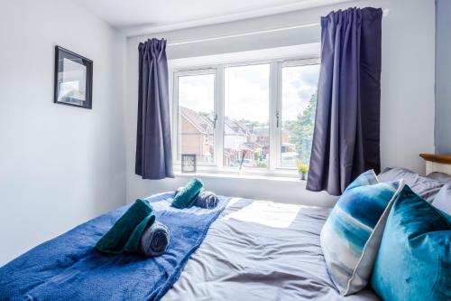 a bedroom with a bed with blue pillows and a window at Stylish 3BR House - free parking - fast WI-FI- smart tv in Bristol