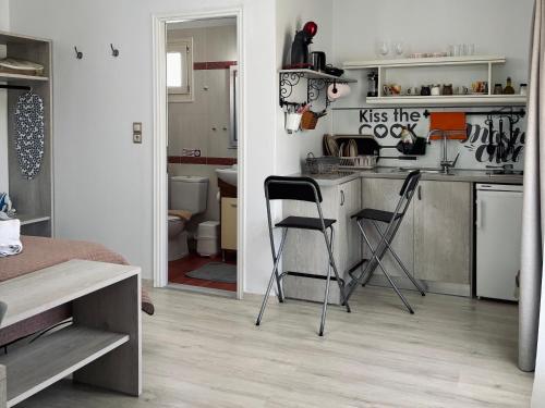 a kitchen with a counter and two chairs in a room at Orama Milos in Adamas