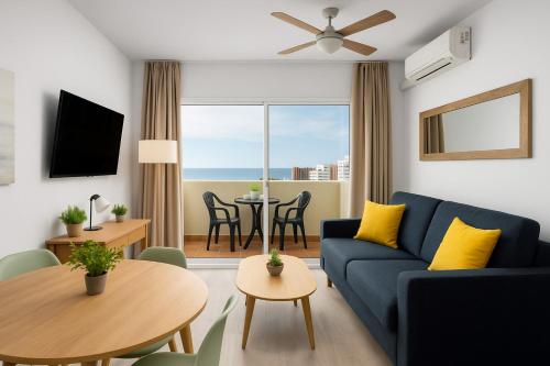 salon z niebieską kanapą i stołem w obiekcie BenalBeach Premium Apartments by Alfresco Stays w mieście Benalmádena
