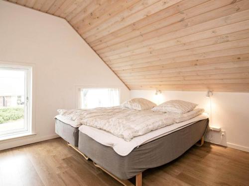 a large bed in a room with a wooden ceiling at Holiday home with sauna, whirlpool- Type1 in Blåvand