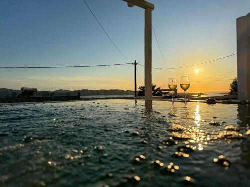 two wine glasses sitting in the water at sunset at La vie est belle luxury apartment BBQ jacuzzi&view in Pounda