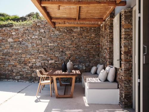 a patio with a table and a brick wall at Stamna Sifnos a member of Design Hotels in Sifnos