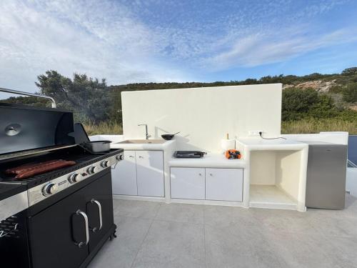 a white kitchen with a stove and a counter at La vie est belle luxury apartment BBQ jacuzzi&view in Pounda