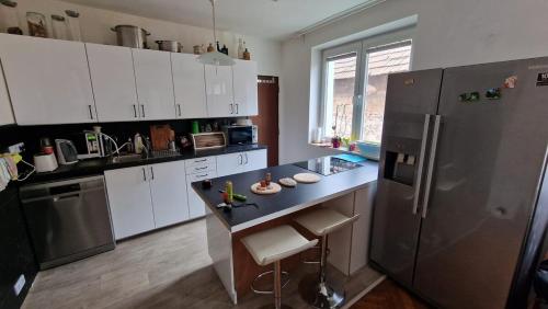a kitchen with white cabinets and a black refrigerator at Big House with beautiful city view, gym,BBQ garden and own parking in Žilina