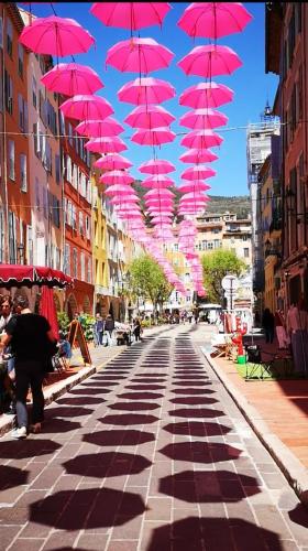 une rangée de parasols roses suspendus au-dessus d'une rue dans l'établissement Authentic Old Town Center of Grasse, à Grasse