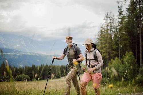 two people with backpacks walking in a field at Hotel Waldfrieden in Schladming