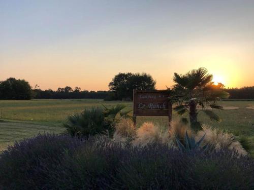 a sign in a field with the sunset in the background at Camping le Ranch - Naujac sur Mer in Naujac-sur-Mer