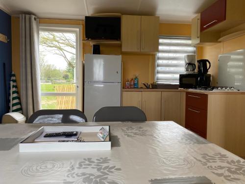 une cuisine avec une table et un réfrigérateur blanc dans l'établissement Mobil home cœur de Vendée, à La Boissière-de-Montaigu