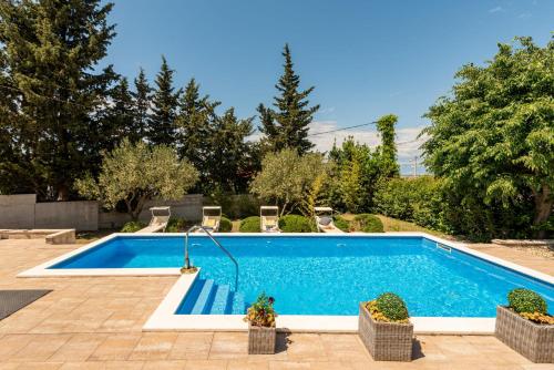 a swimming pool in a yard with chairs around it at Villa Meštrović ZadarVillas in Zadar