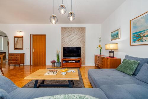 a living room with a blue couch and a table at Villa Meštrović ZadarVillas in Zadar