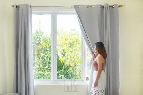 a woman in a white dress looking out of a window at Hale lua Villa near Sanur Port in Sanur