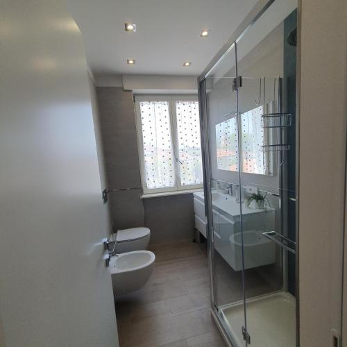 a bathroom with a toilet and a glass shower at Tonfano Waterfront Penthouse in Marina di Pietrasanta