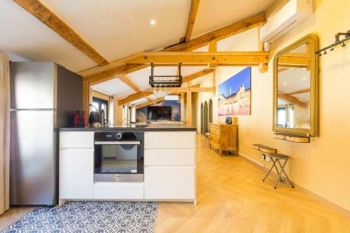 une cuisine avec des armoires blanches et un réfrigérateur en acier inoxydable dans l'établissement L'Echappée Ducale, à Dijon