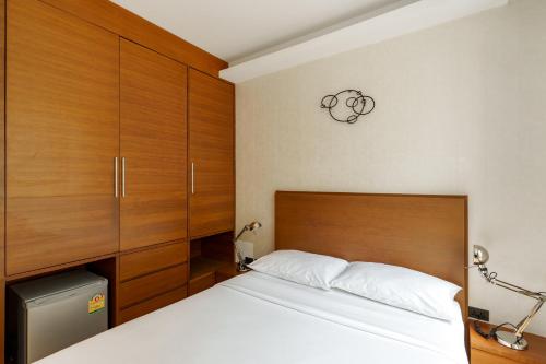 a bedroom with a bed and wooden cabinets at Marvin Suites Hotel in Bangkok
