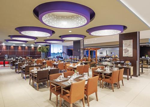 a dining room with tables and chairs and purple lights at Aston Purwokerto Hotel & Conference Center in Purwokerto