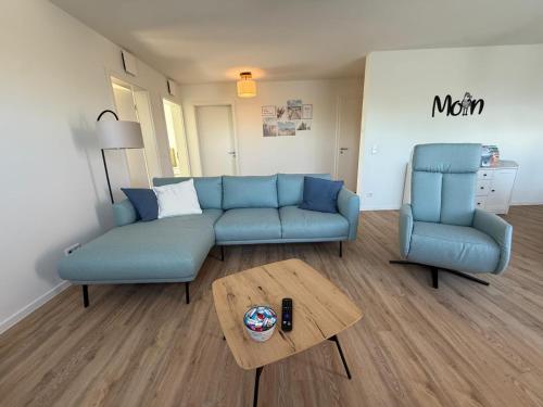 een woonkamer met een blauwe bank en twee stoelen bij Ferienwohnung Deichliebe in Butjadingen