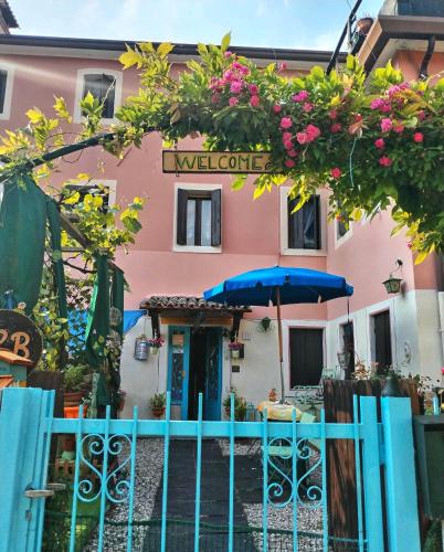 a pink building with a fence and a blue umbrella at Art B&B La Casa del Pittore in Revine Lago