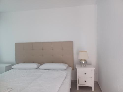 a white bedroom with a bed and a nightstand with a lamp at Villa Can Goldi con vistas al mar in Sant Josep
