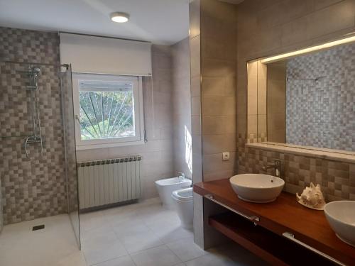 a bathroom with two sinks and a shower and a toilet at Villa Can Goldi con vistas al mar in Sant Josep