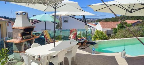 a table and chairs with umbrellas next to a pool at Kyrios Arts Atelier with use of private swimming pool in Carrascal