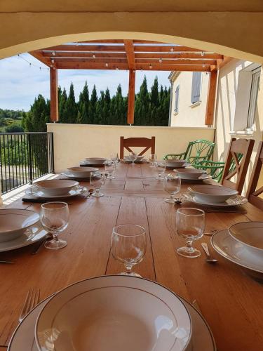 a long wooden table with glasses and plates on it at Gîte des Falaises 10 à 12 personnes in Souspierre