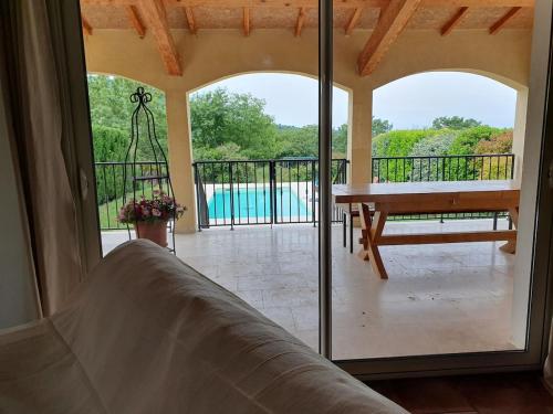 a room with a balcony with a table and a pool at Gîte des Falaises 10 à 12 personnes in Souspierre