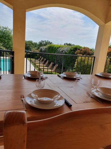 a wooden table with plates and wine glasses on it at Gîte des Falaises 10 à 12 personnes in Souspierre