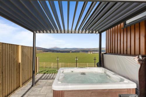 a hot tub on a patio with a view of a field at Arrochar View in Langbank