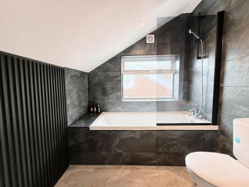 a bathroom with a bath tub and a window at Bee Stays - Rostherne House in Warrington